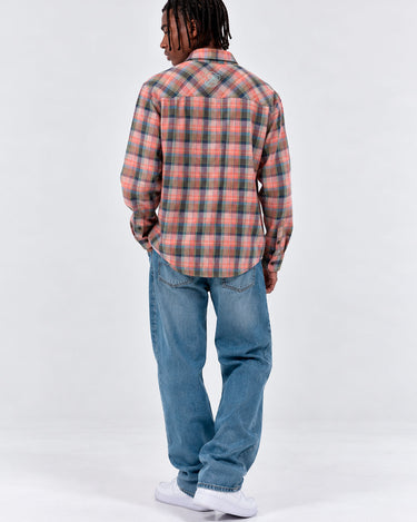 Camisa de franela de cuadros en tonos rosa y azul, vista trasera, combinada con jeans claros.