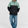 Cortavientos impermeable en negro y verde, con capucha y logo visible en el pecho, modelo masculino con jeans claros.