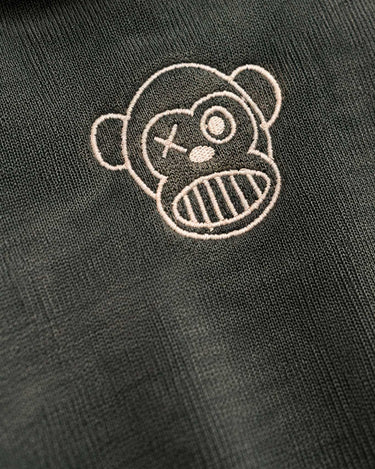 Sudadera verde oscuro con bordado de un mono con expresión divertida y detalles en color claro.