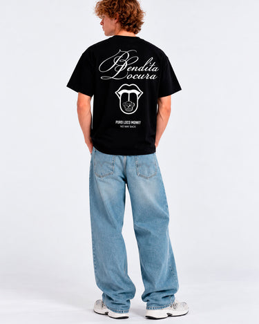 Camiseta negra con texto 'Bendita Locura' y logo de Loco Monky en la espalda, modelo de pie con jeans claros.