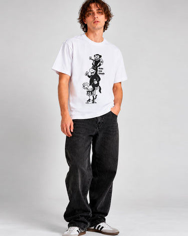 Camiseta blanca con diseño gráfico en negro, modelo masculino con pantalones oscuros y zapatillas blancas.