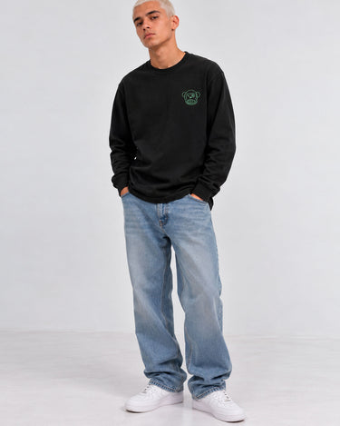 Camiseta de manga larga negra con diseño de mono en el pecho, combinada con jeans claros y zapatillas blancas.