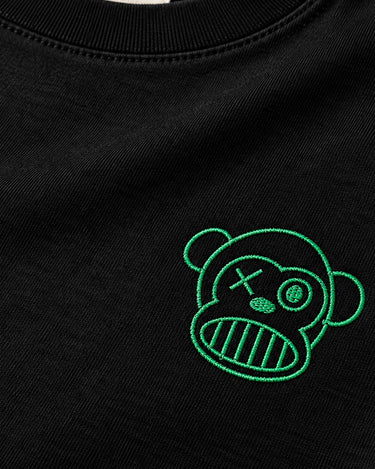 Camiseta negra de manga larga con bordado verde de un mono con expresión divertida en el pecho.