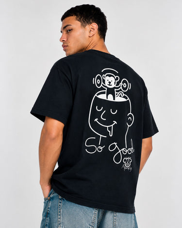 Camiseta negra con diseño gráfico de un rostro y un mono levantando pesas en la espalda, texto 'So Good'.