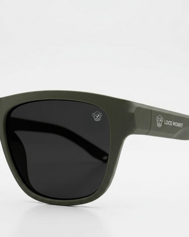 Gafas de sol unisex Loco Monky Dark Green, montura verde oliva y lentes oscuros con logo en la patilla.