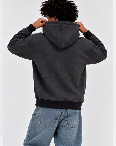Sudadera con capucha gris oscuro, vista trasera, con puños y cintura en negro, combinada con jeans claros.
