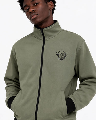 Chaqueta sin capucha en color oliva con logo de mono en el pecho, cierre frontal y puños negros.