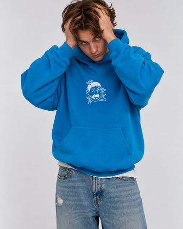 Sudadera unisex azul con capucha y diseño blanco en el pecho, modelo con manos en la cabeza.