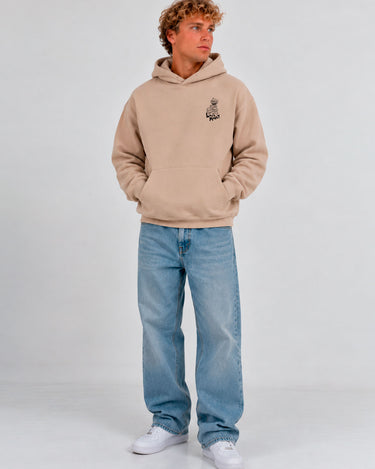 Sudadera unisex color arena con capucha, logo de Loco Monky en el pecho, pantalones de mezclilla claros.