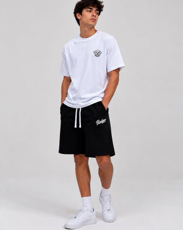 Pantalones cortos negros con cordón blanco y logo en la pierna, combinados con camiseta blanca.