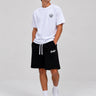 Pantalones cortos negros con cordón blanco y logo en la pierna, combinados con camiseta blanca.