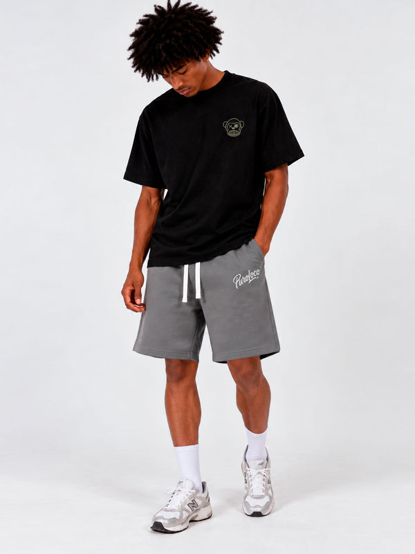 Bermuda de color gris oscuro con cordón blanco, logo en la pierna, modelo masculino con camiseta negra.