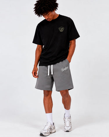 Bermuda de color gris oscuro con cordón blanco, logo en la pierna, modelo masculino con camiseta negra.