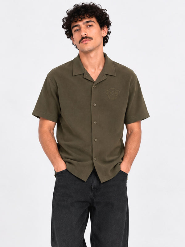 Camisa de polo khaki de manga corta con botones y bordado en el pecho, modelo masculino.