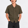 Camisa de polo khaki de manga corta con botones y bordado en el pecho, modelo masculino.