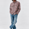 Camisa de franela de cuadros en tonos rosa y gris, con dos bolsillos frontales, combinada con jeans claros.
