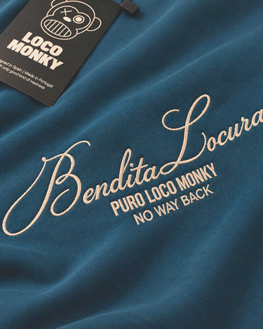 Camiseta azul con bordado en color claro que dice 'Bendita Locura' y etiqueta de Loco Monky