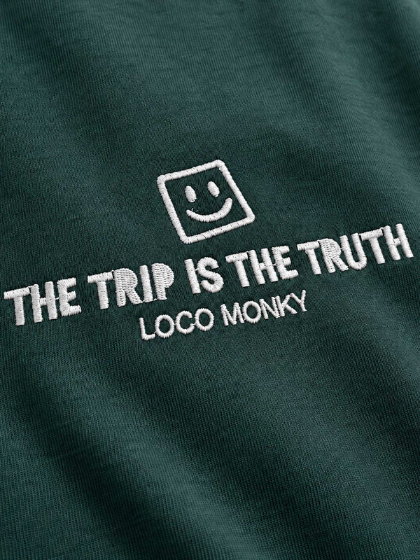 Camiseta boxy unisex color verde oscuro con bordado blanco que dice 'THE TRIP IS THE TRUTH' y logo de Loco Monky.