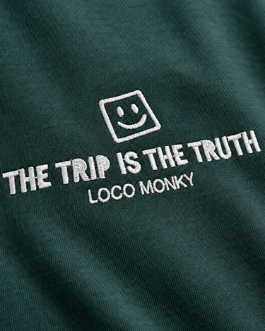 Camiseta boxy unisex color verde oscuro con bordado blanco que dice 'THE TRIP IS THE TRUTH' y logo de Loco Monky.