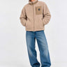 Chaqueta Sherpa unisex color beige con cremallera y bolsillo frontal, modelo con jeans y zapatillas blancas.