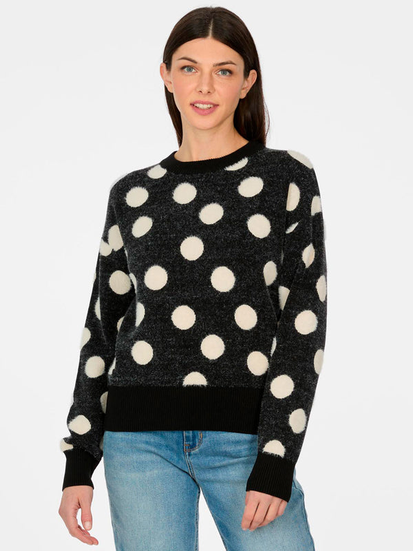 Jersey de mujer negro con grandes puntos blancos, cuello redondo y puños acanalados, fondo blanco.