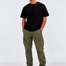 Pantalón cargo verde con bolsillos laterales, combinado con camiseta negra y zapatillas blancas.