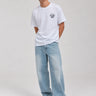 Pantalón vaquero azul claro con corte amplio, combinado con camiseta blanca y zapatillas blancas.