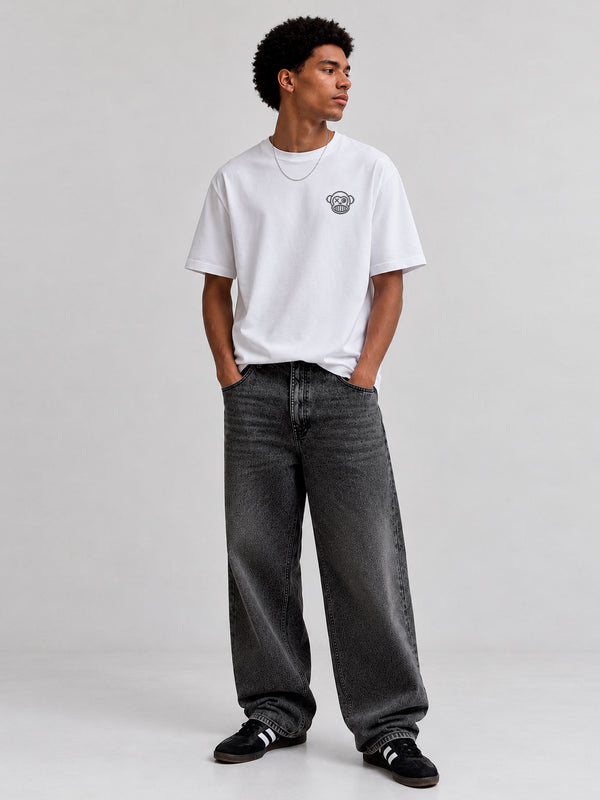 Pantalón vaquero negro lavado con corte amplio, combinado con camiseta blanca y zapatillas negras.