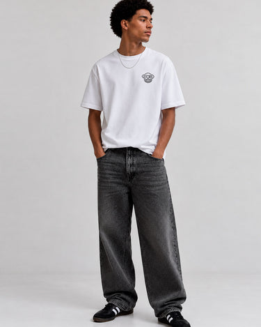 Pantalón vaquero negro lavado con corte amplio, combinado con camiseta blanca y zapatillas negras.
