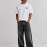 Pantalón vaquero negro lavado con corte amplio, combinado con camiseta blanca y zapatillas negras.