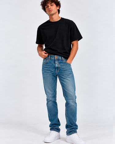 Pantalón vaquero azul claro para hombre, con camiseta negra y zapatillas blancas, fondo blanco