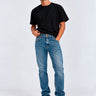 Pantalón vaquero azul claro para hombre, con camiseta negra y zapatillas blancas, fondo blanco