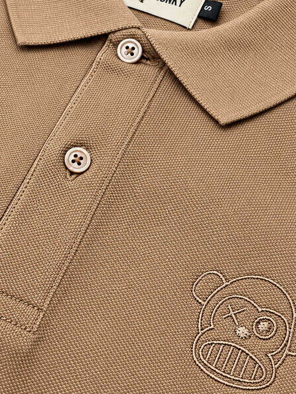 Polo de hombre color caramelo con bordado de un mono y botones claros, etiqueta visible de Loco Monky.