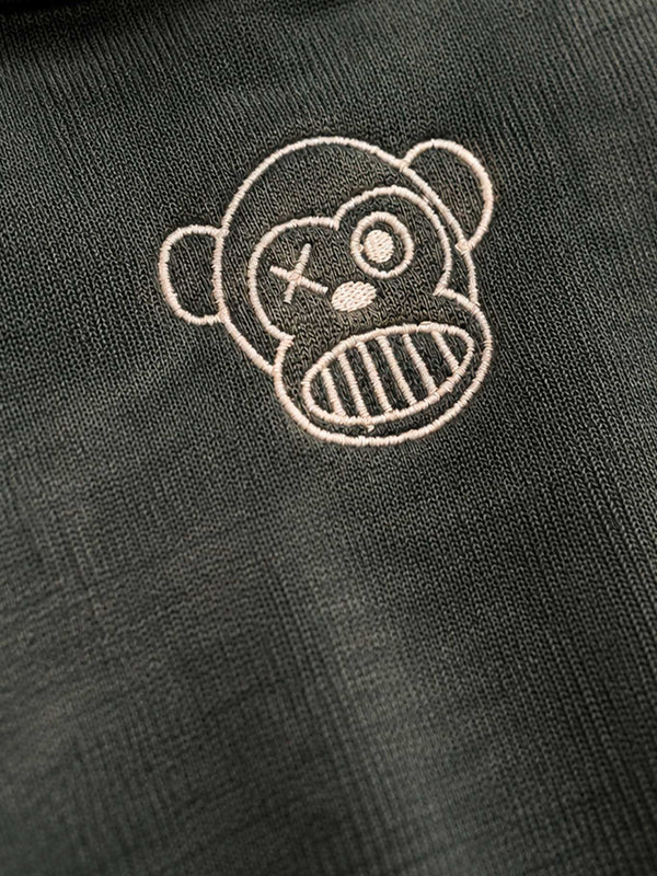 Sudadera verde oscuro con bordado de un mono con expresión divertida y detalles en color claro.