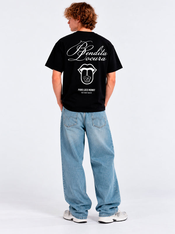 Camiseta negra con texto 'Bendita Locura' y logo de Loco Monky en la espalda, modelo de pie con jeans claros.