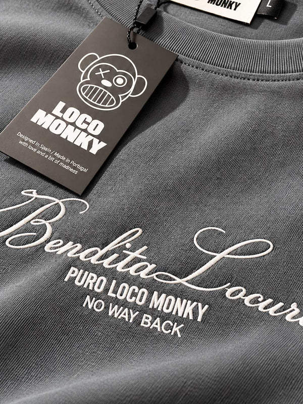 Camiseta gris oscuro con bordado blanco que dice 'Bendita Locura' y etiqueta de la marca Loco Monky.