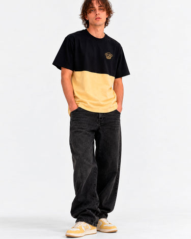 Camiseta de hombre en amarillo suave y negro, con logo de Loco Monky en el pecho, combinada con pantalones oscuros.