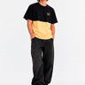 Camiseta de hombre en amarillo suave y negro, con logo de Loco Monky en el pecho, combinada con pantalones oscuros.