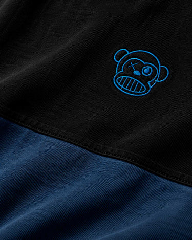 Camiseta en azul oscuro y negro con bordado de un mono sonriente en el pecho.
