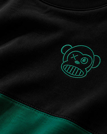 Camiseta negra con detalles en verde oscuro y bordado de un oso con cara sonriente y ojos cruzados