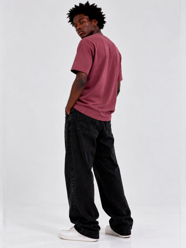 Camiseta de color púrpura con bordado, modelo de espaldas, usando pantalones negros y zapatillas blancas.
