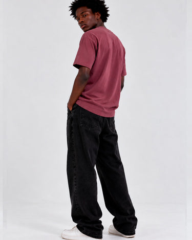 Camiseta de color púrpura con bordado, modelo de espaldas, usando pantalones negros y zapatillas blancas.