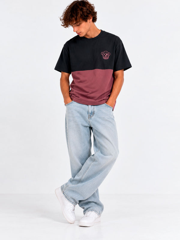 Camiseta unisex negra y morada con logo de Loco Monky, modelo de pie con jeans claros y zapatillas blancas.
