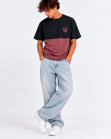 Camiseta unisex negra y morada con logo de Loco Monky, modelo de pie con jeans claros y zapatillas blancas.