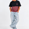 Camiseta unisex negra y morada con logo de Loco Monky, modelo de pie con jeans claros y zapatillas blancas.