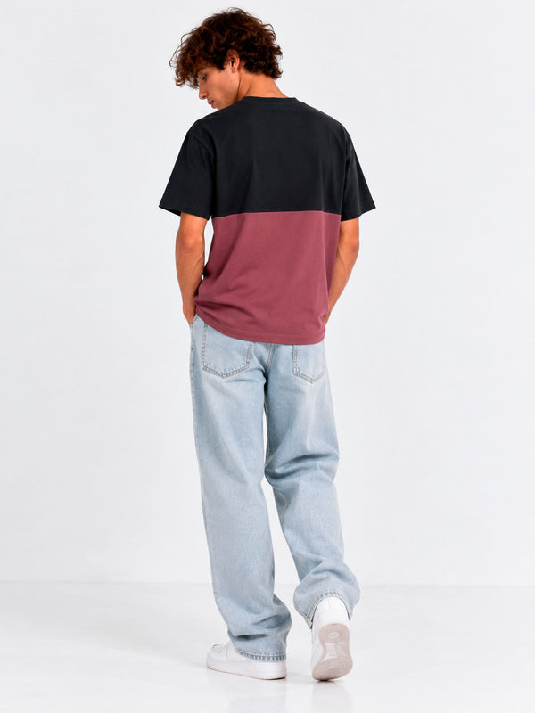 Camiseta unisex en negro y morado, vista trasera, combinada con jeans claros y zapatillas blancas.