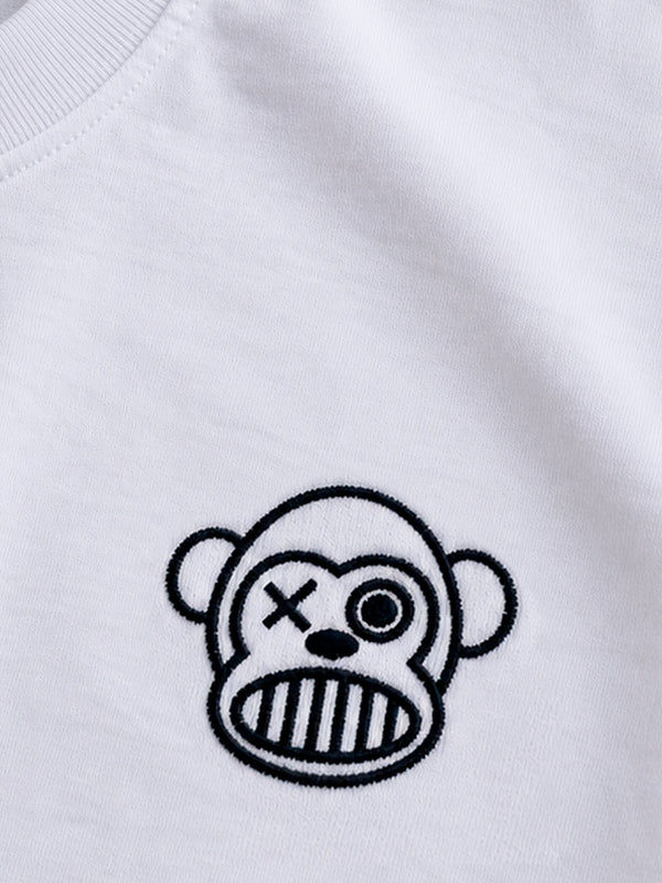 Camiseta blanca con bordado de un mono con un ojo cruzado y una boca de rayas en el pecho.