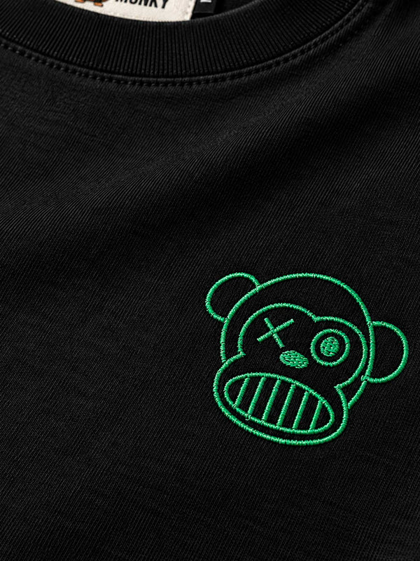 Camiseta negra de manga larga con bordado verde de un mono con expresión divertida en el pecho.