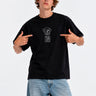 Camiseta negra unisex con diseño de oso y texto 'Puro Loco' en el pecho, modelo señalando el diseño.