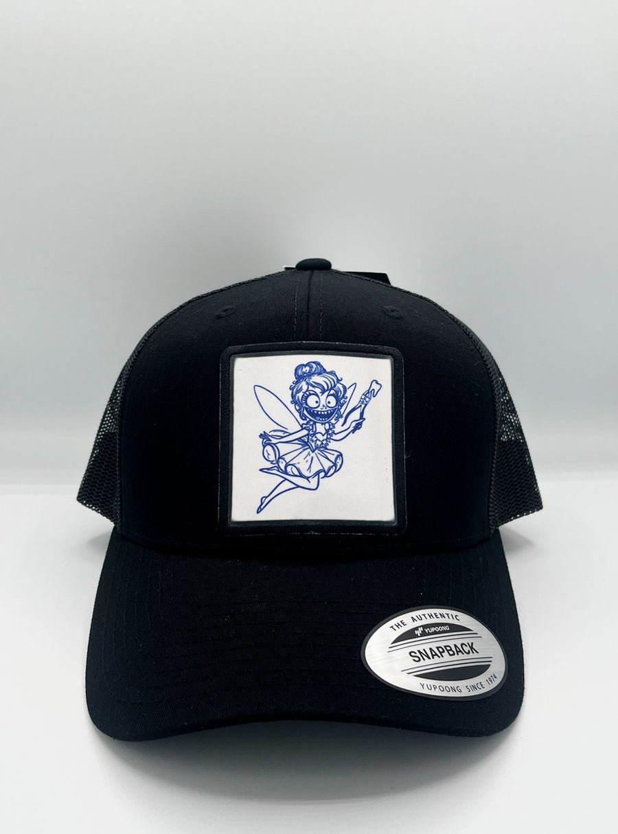 Gorra trucker Tooth Fairy de Loco Monky en negro, con rejilla blanca y parche del hada de los dientes en el frontal.